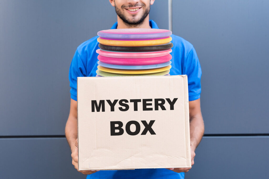 Photo of a man holding a disc golf mystery box